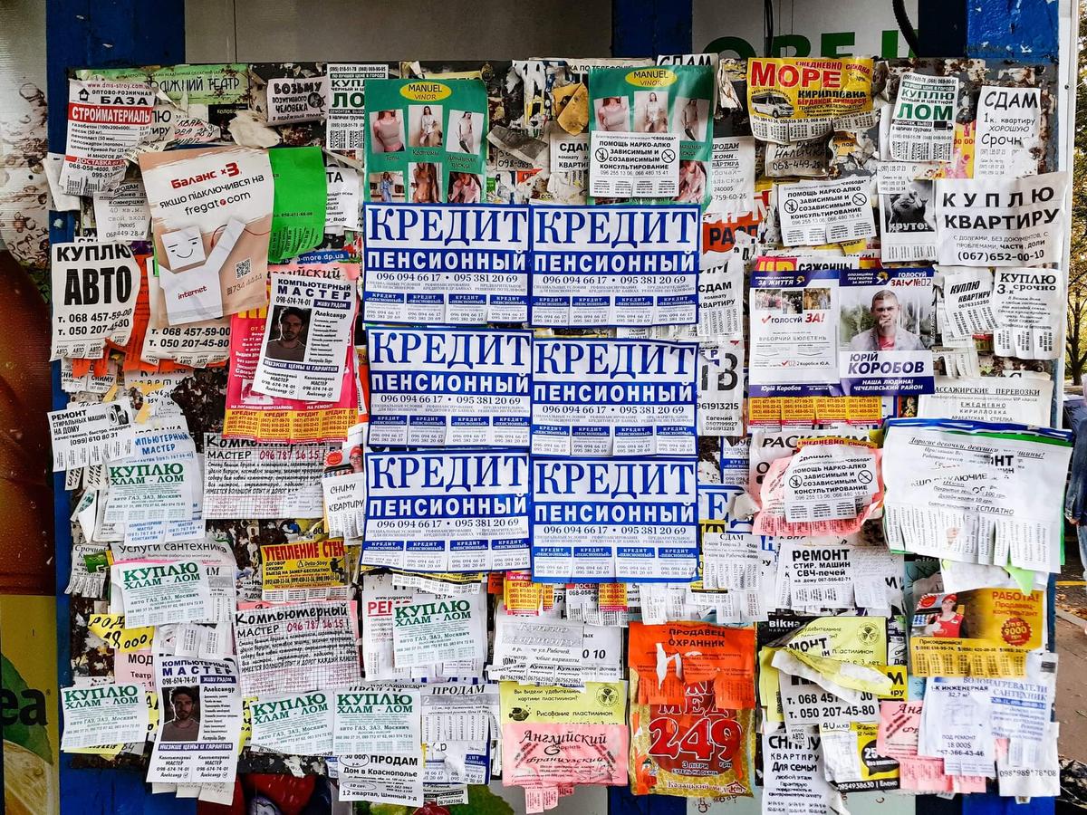A bunch of paper ads on a wall on the streets.